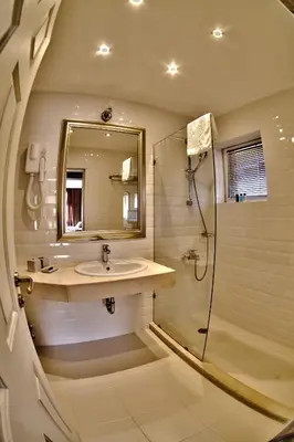 a bathroom with a sink and a shower with a mirror at Meg-Lozenetz Hotel in Sofia
