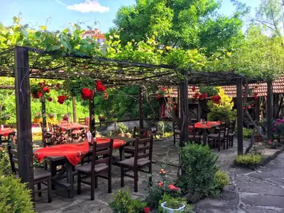 a garden with tables and chairs under a pergola at Troyan Plaza Hotel in Troyan