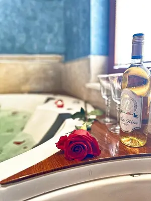 a bottle of alcohol and a rose on a table at Spa Hotel Rich in Velingrad