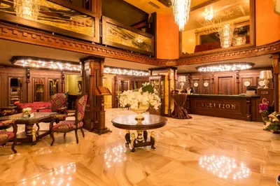 a lobby with tables and chairs in a building at Spa Hotel Rich in Velingrad