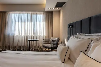 a hotel room with a bed and a chair and a window at Hotel VEGA Sofia in Sofia