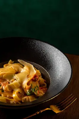 a plate of pasta in a pan with a fork at Rosslyn Central Park Hotel Sofia in Sofia