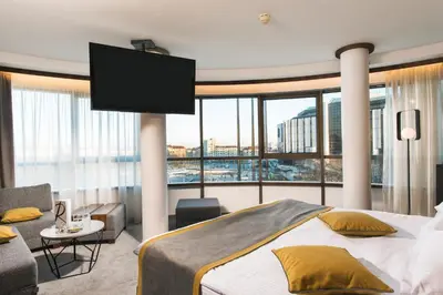 a bedroom with a large bed and a flat screen tv at Rosslyn Central Park Hotel Sofia in Sofia