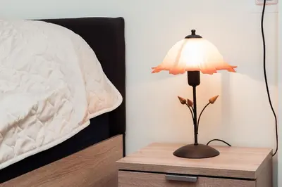 a lamp on a wooden table next to a bed at Central Academic Apartment Sofia in Sofia