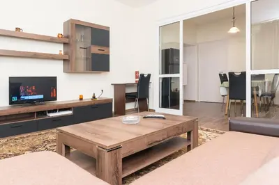 a living room with a wooden table and a tv at Central Academic Apartment Sofia in Sofia
