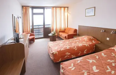 a hotel room with two beds and a chair at Hotel Samokov in Borovets