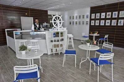 a man standing at a counter in a room with tables and chairs at Hotel Samokov in Borovets