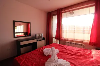 a bedroom with a red bed and a mirror at Mountview Lodge Apartments in Bansko