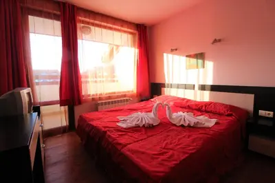 a bedroom with a red bed with two towels on it at Mountview Lodge Apartments in Bansko