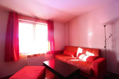 a living room with a red couch and a window at Mountview Lodge Apartments in Bansko