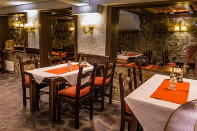 a dining room with tables and chairs in a restaurant at Aneli Hotel in Bansko