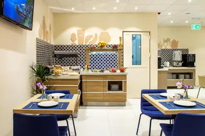 a kitchen with two tables and blue chairs at Best Western Terminus Hotel in Sofia
