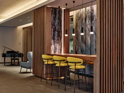 a bar with yellow stools in a room with a piano at Crowne Plaza Sofia by IHG in Sofia