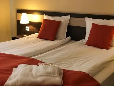 two beds in a hotel room with red and white pillows at Apart Hotel Dream in Bansko