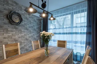 a dining room table with a vase of flowers on it at Grand Vitosha Apartments in Sofia