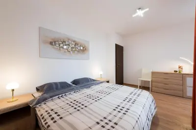 a white bedroom with a bed and a dresser at Grand Vitosha Apartments in Sofia