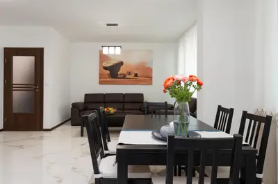 a dining room with a table with a vase of flowers at Grand Vitosha Apartments in Sofia