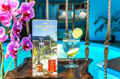 a glass of wine and a book on a table with flowers at Chateau Montagne Hotel Troyan in Troyan