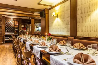 a row of tables in a restaurant with white table linens at Chateau Montagne Hotel Troyan in Troyan