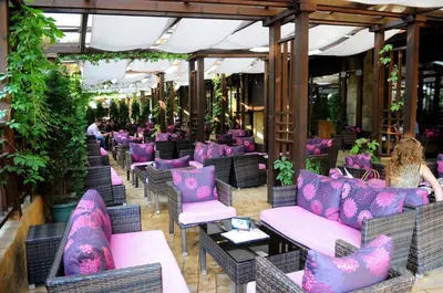 a patio with pink and purple chairs and tables at Gardenia Park Hotel in Bansko