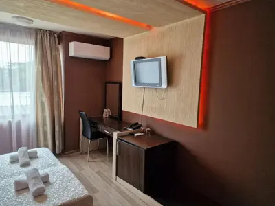 a hotel room with a desk and a tv on the wall at Hotel Gabi in Plovdiv