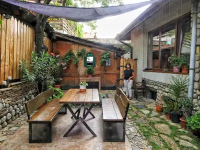 a woman standing in a patio with a table and benches at Kralev Dvor Hotel in Bansko