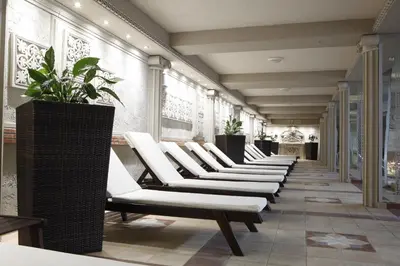 a row of white lounge chairs in a hallway at Strimon Garden Medical SPA Hotel in Kyustendil