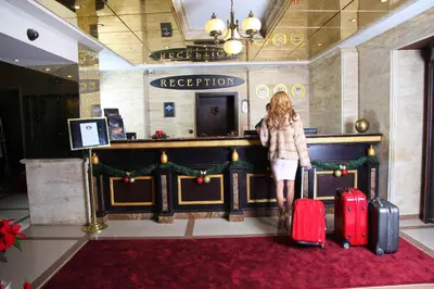 a woman standing in a lobby with two suitcases at Strimon Garden Medical SPA Hotel in Kyustendil
