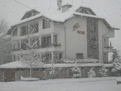 a house covered in snow in front at Rahoff hotel in Bansko