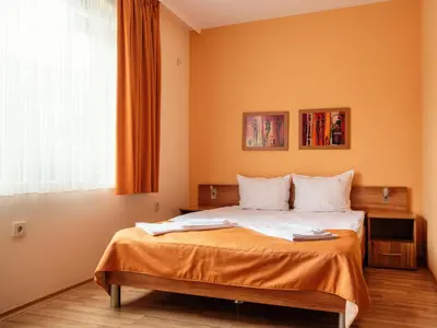 a bedroom with a bed with orange walls and a window at Bright House in Plovdiv