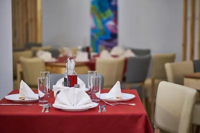 a table with a red table cloth and plates and glasses at Mountain Paradise next to Sunrise in Bansko