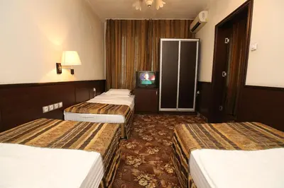 a hotel room with three beds and a tv at Hotel & Restaurant The House in Sofia