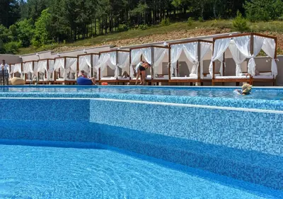 a blue swimming pool with a row of white chairs at Grand Hotel Velingrad in Velingrad