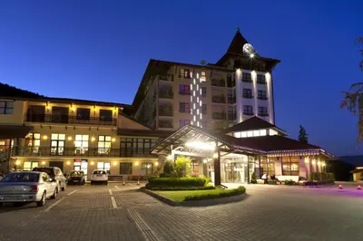 a large building with a car parked in a parking lot at Grand Hotel Velingrad in Velingrad