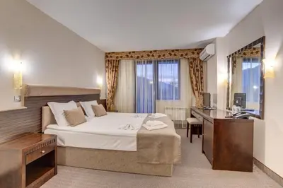a bedroom with a bed and a desk and a television at Hotel Bansko SPA & Holidays - Free Parking in Bansko