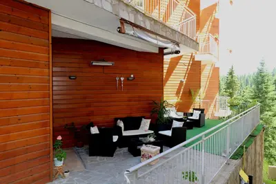 a patio with couches and chairs on a balcony at Dafovska Hotel in Pamporovo
