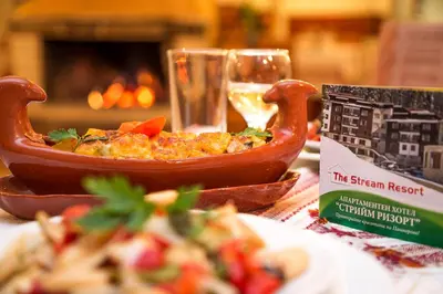 a table with a bowl of food and a book at The Stream Resort Pamporovo in Pamporovo