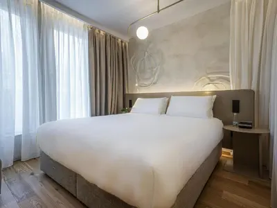 a large white bed in a room with windows at Maison Sofia - MGallery in Sofia