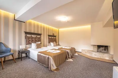 a hotel room with two beds and a fireplace at Wellness Hotel Bulgaria in Bansko