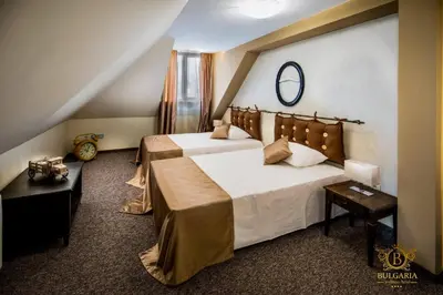 a bedroom with two beds and a mirror on the wall at Wellness Hotel Bulgaria in Bansko