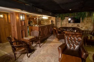 a bar with leather chairs and a couch and a television at Wellness Hotel Bulgaria in Bansko