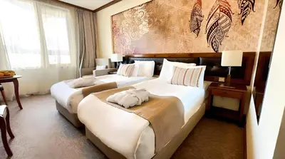 two beds in a hotel room with a large mural at Platinum Hotel and Casino Bansko in Bansko