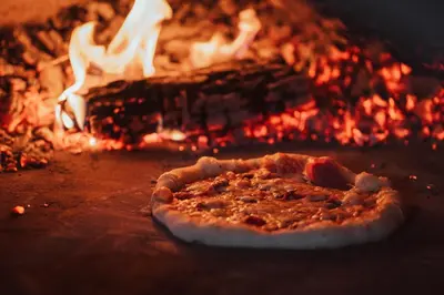 a pizza is sitting in front of a fire at Katarino SPA Hotel in Bansko