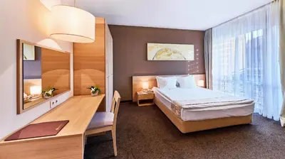 a hotel room with a bed and a desk and a table at Lucky Bansko Aparthotel SPA & Relax in Bansko