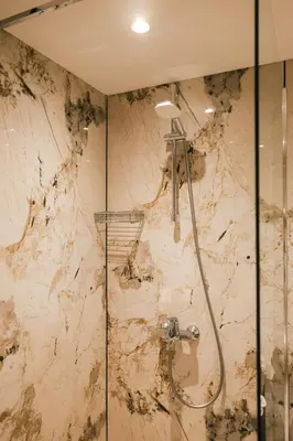 a bathroom with a shower with a marble wall at Triada Hotel in Sofia