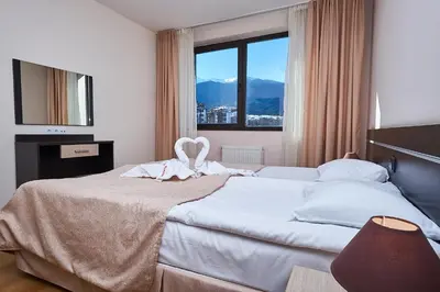 a bedroom with a large white bed with a window at Sunrise Park Hotel Bansko - Free Wellness in Bansko