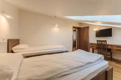 a room with two beds and a desk with a television at Musala Hotel in Borovets