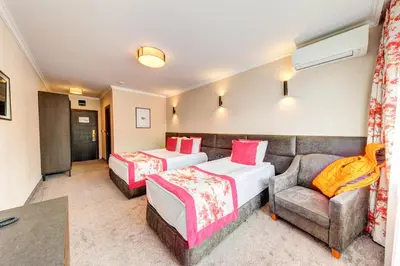 a hotel room with two beds and a couch at SPA Hotel Kiparis in Smolyan