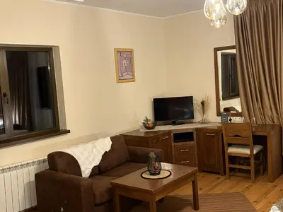a living room with a couch and a tv and a table at Hotel Smilen in Smolyan
