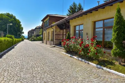 a cobblestone street in front of a house with flowers at Hotel Bojur & Bojurland Apartment Complex in Bansko